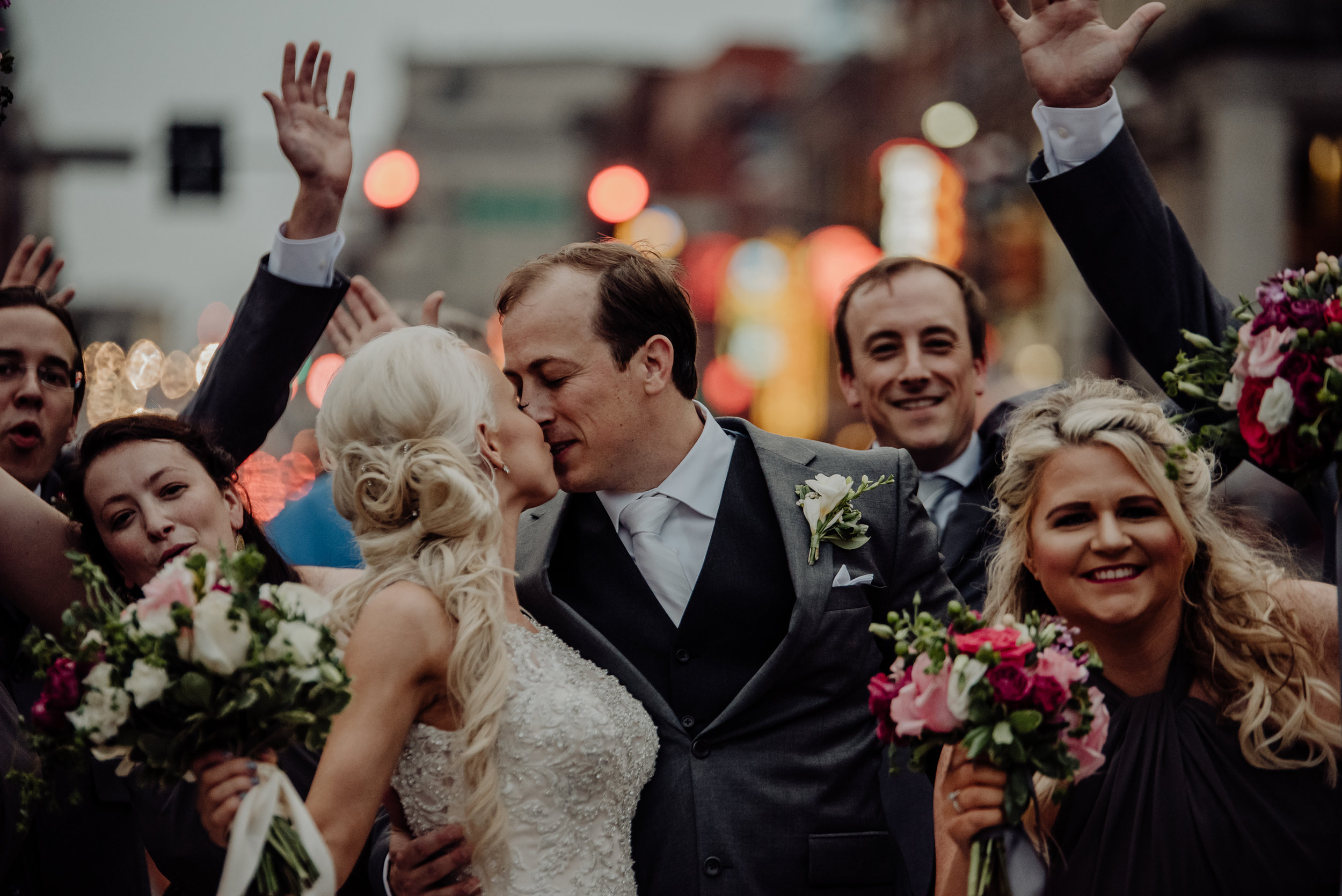 bride and groom kissing surrounded by their wedding party in downtown nashville