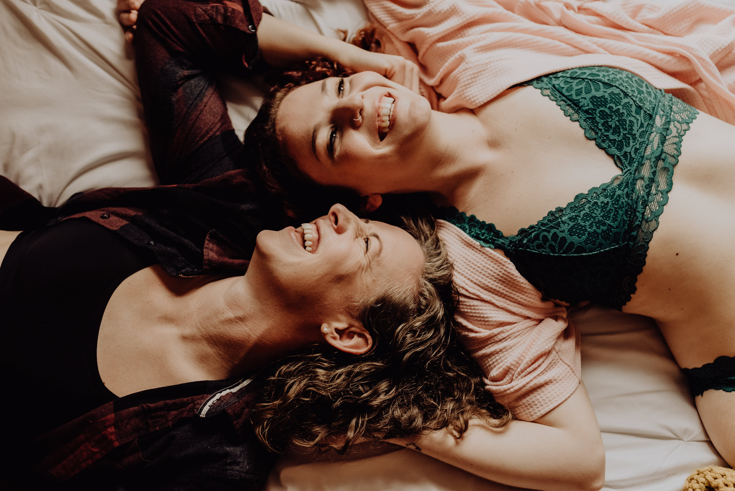 lesbian couple laughing together during their couples boudoir session