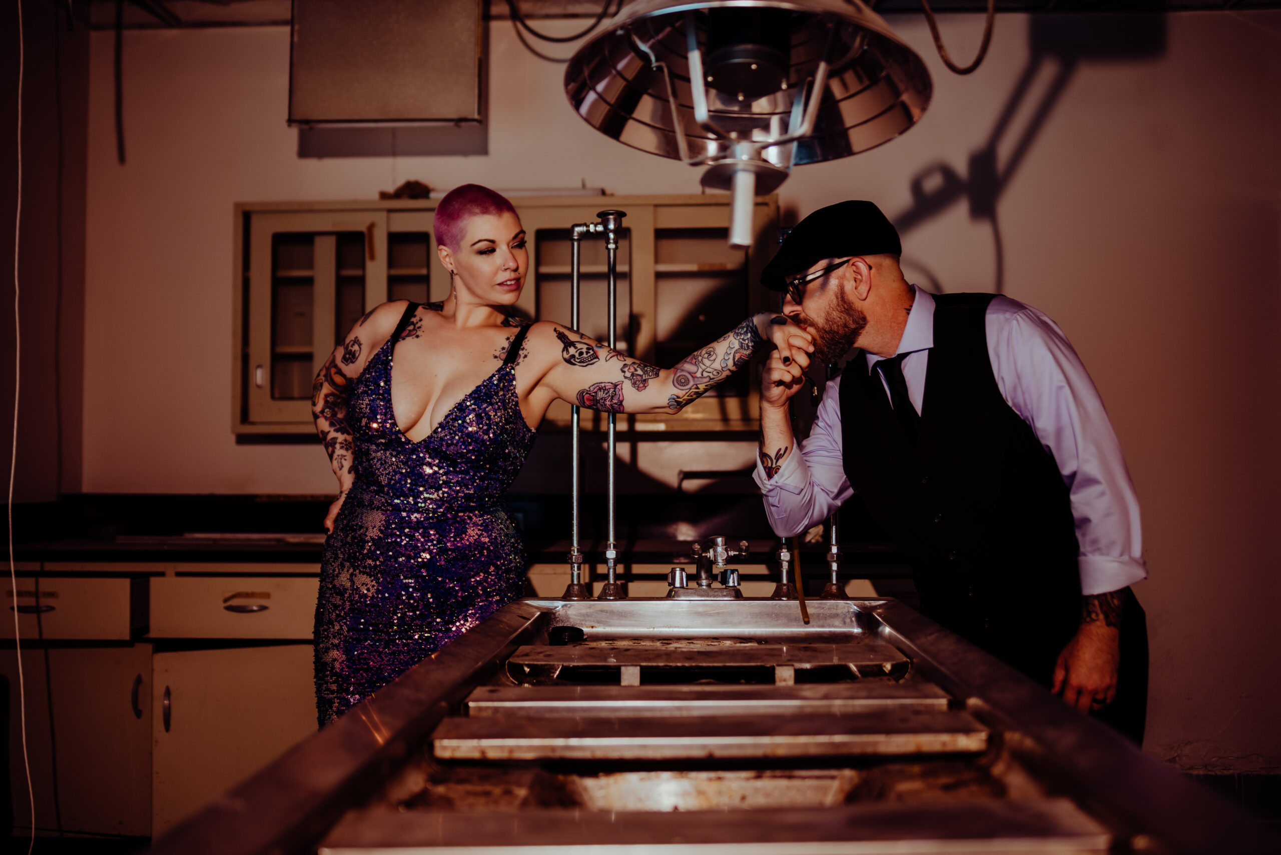 woman with shaved pink hair in a sequin dress having her hand kissed by a man at their elopement in an abandoned hospital in Nashville