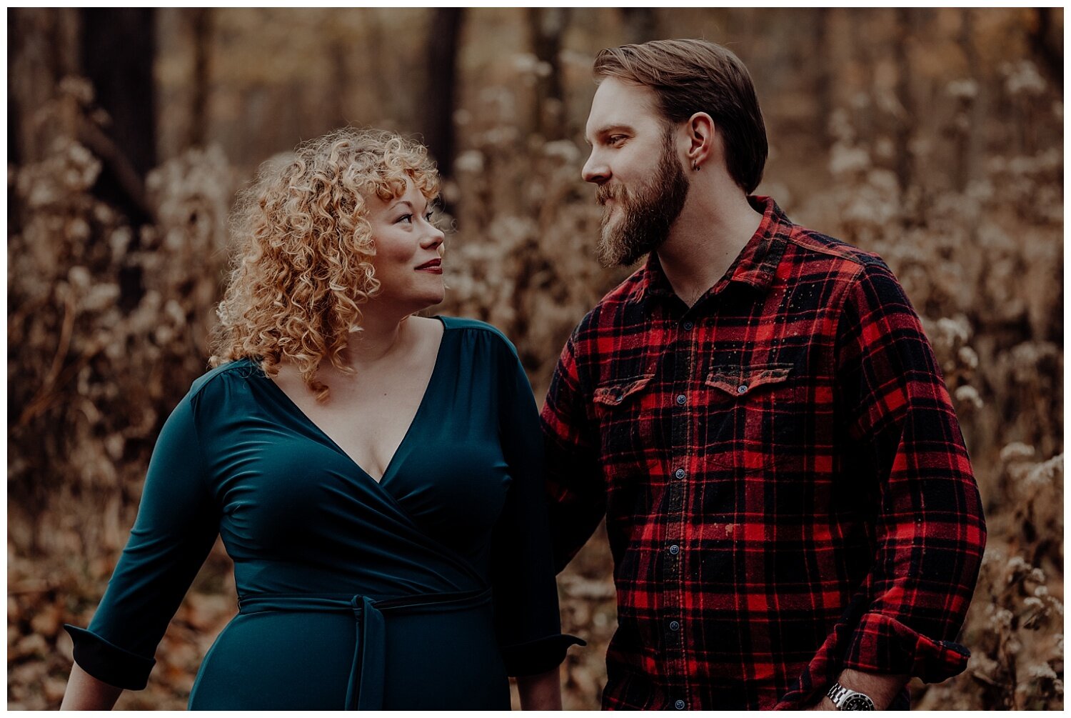 woman with curly hair and man with a beard looking lovingly at one another outside during the fall at their nashville engagement session