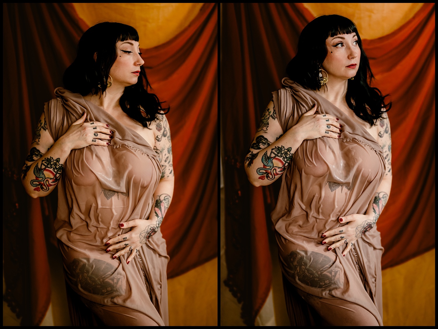 A woman with dark hair and tattoos poses in a flowing, sheer taupe gown, embodying a classical elegance. Against a warm backdrop with red and orange fabric drapes, her expression remains contemplative as her hand rests on her chest, enhancing the wet look of her skin.