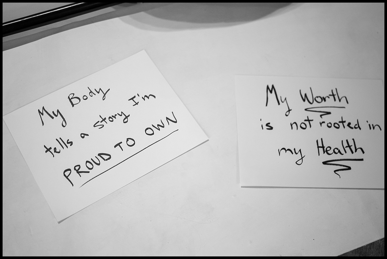 Two handwritten notes on white paper celebrate body acceptance: one reads, My body tells a story I’m proud to own. The other says, My worth is not rooted in my health. Both reflect the spirit of self-love found in a Boudoir Empowerment Shoot.