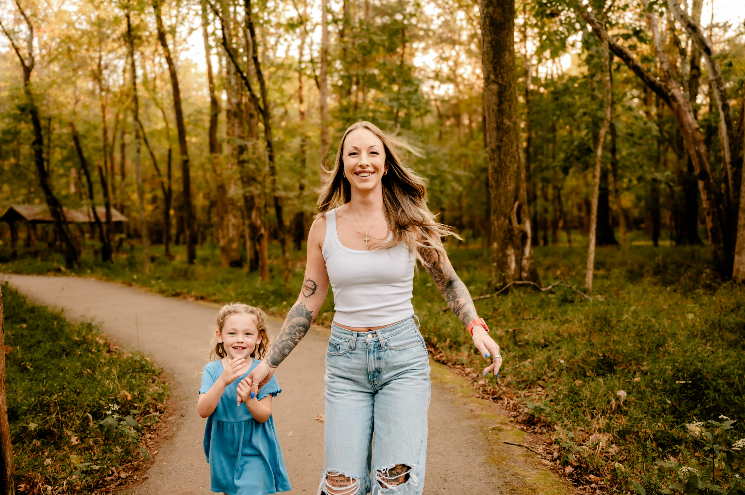 A woman and a girl walk on a path in the woods, captured beautifully by a Nashville Family Photographer.