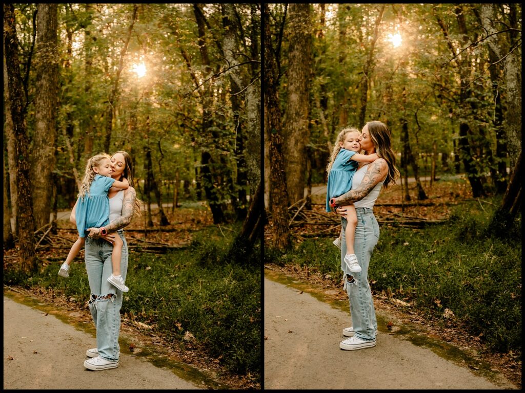 A woman in ripped jeans and a tank top holds a young girl in a blue dress, sharing a close, affectionate moment on a forest path at sunset. Captured by a Nashville Family Photographer, their Together Session glows with warmth as sunlight filters through the trees.