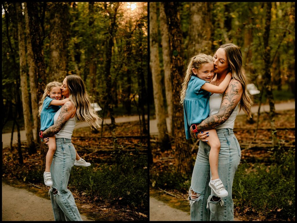 A woman with long hair and tattooed arms hugs a smiling young girl in a blue dress outdoors at sunset. Both appear happy and relaxed, capturing a warm moment perfect for Nashville Family Photography.