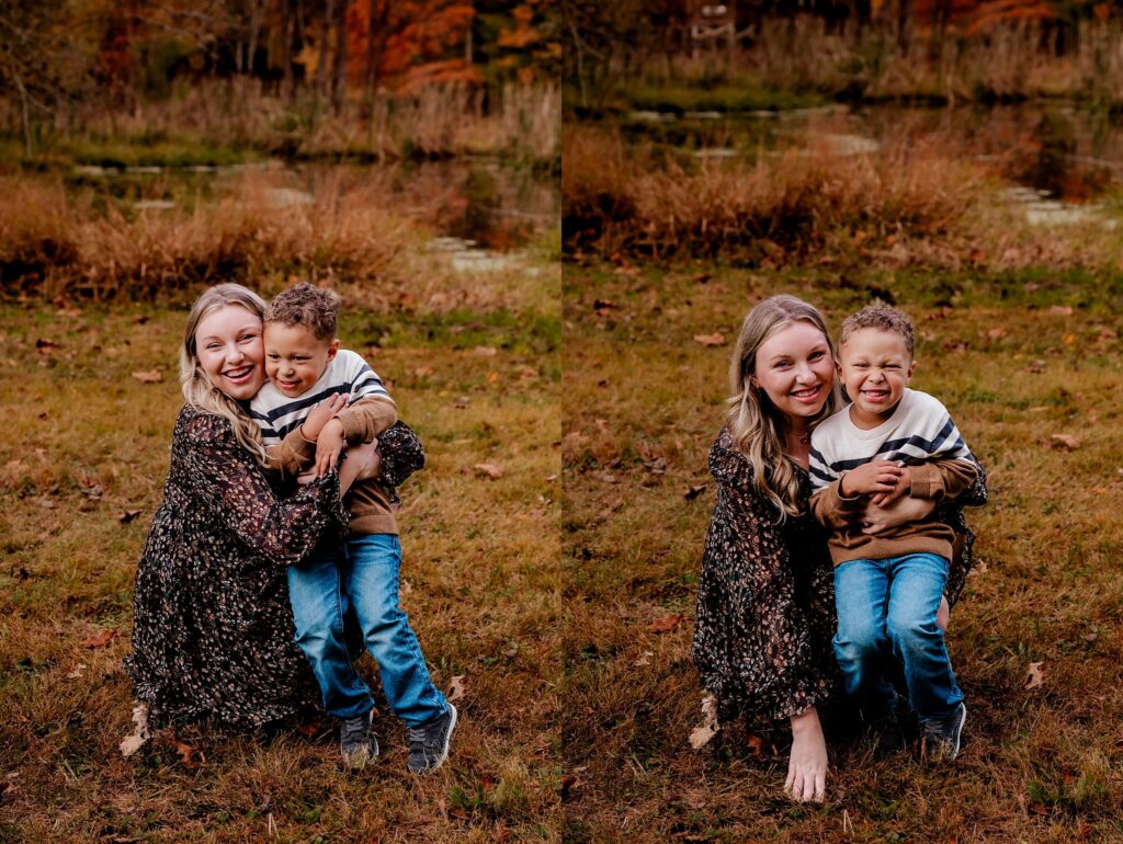 A woman and a young boy smile and laugh together while posing outdoors on grass with autumn foliage and a pond in the background—capturing the joy of a fall family session by a Nashville portrait photographer.