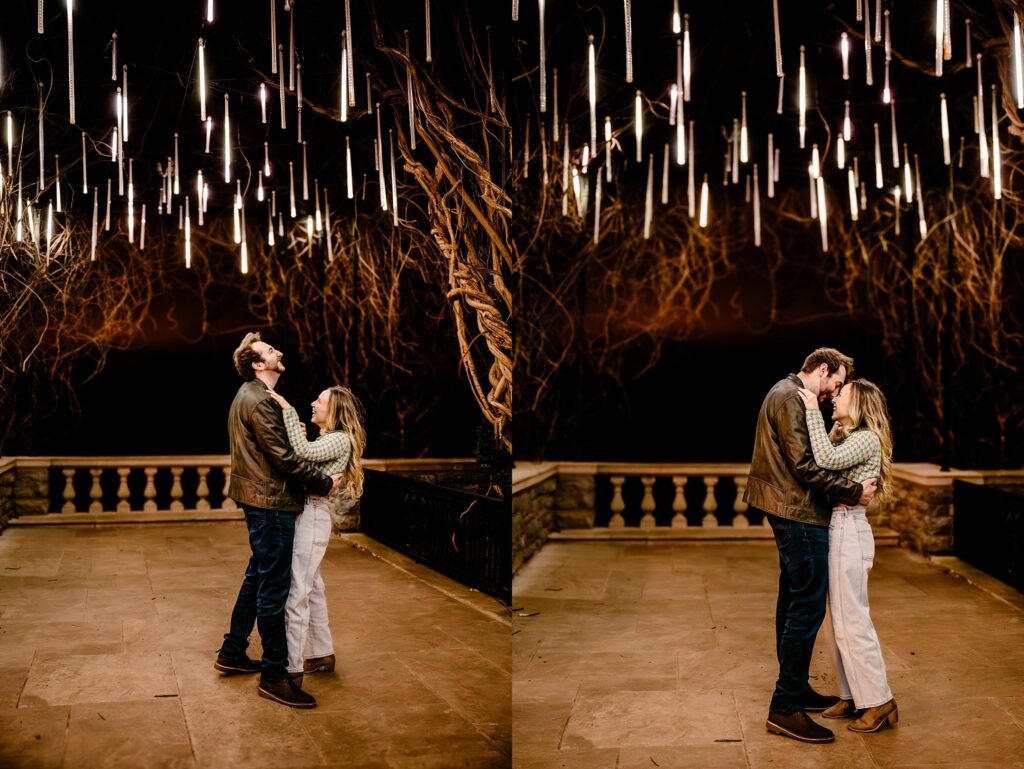 A couple stands close together at night under hanging lights and twisted tree branches, sharing affectionate moments on a stone terrace—captured beautifully by a Nashville Proposal Photographer.