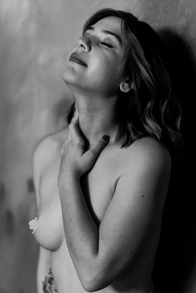 A woman with her hands on her neck exudes confidence in this Nashville boudoir portrait.