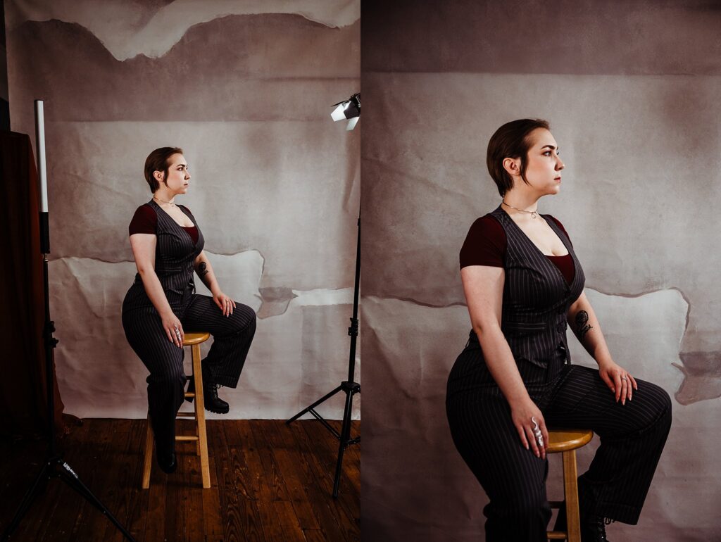 A woman in a pinstripe suit and maroon shirt poses confidently on a wooden stool in a studio with a textured backdrop. Captured by a Nashville creative portrait photographer, the two images showcase her from the side and front with studio lights visible.