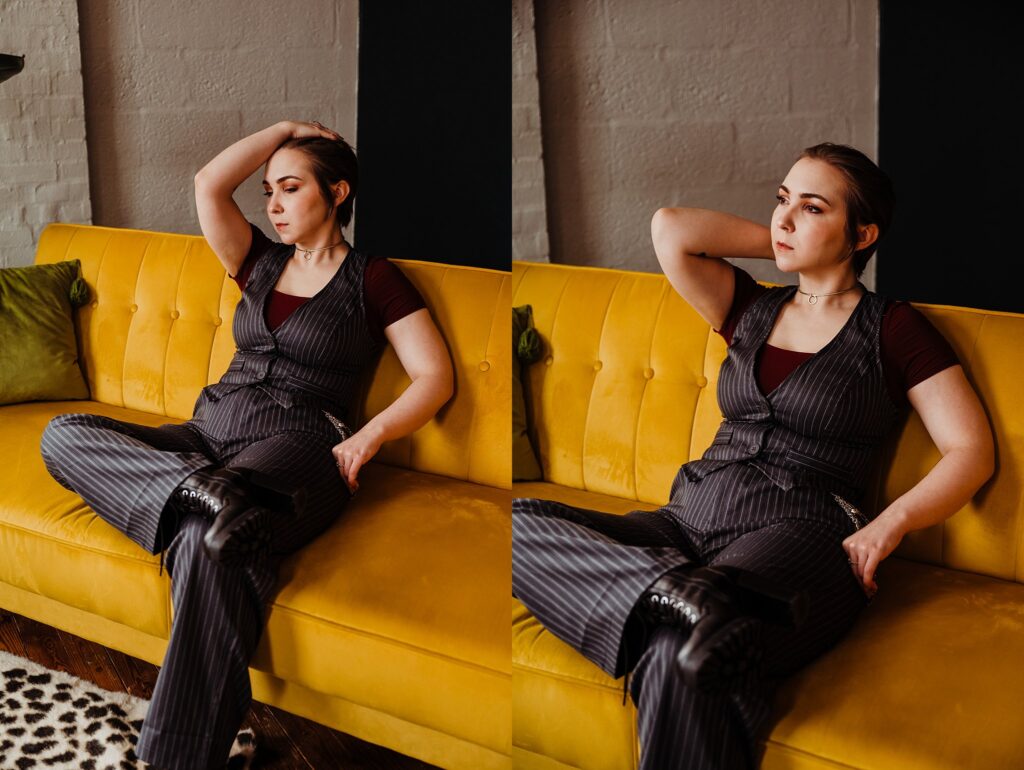 A person with short hair sits on a yellow couch, wearing a pinstripe vest and pants over a maroon shirt. Captured by a Nashville creative portrait photographer, they look thoughtful, with a relaxed but pensive expression.