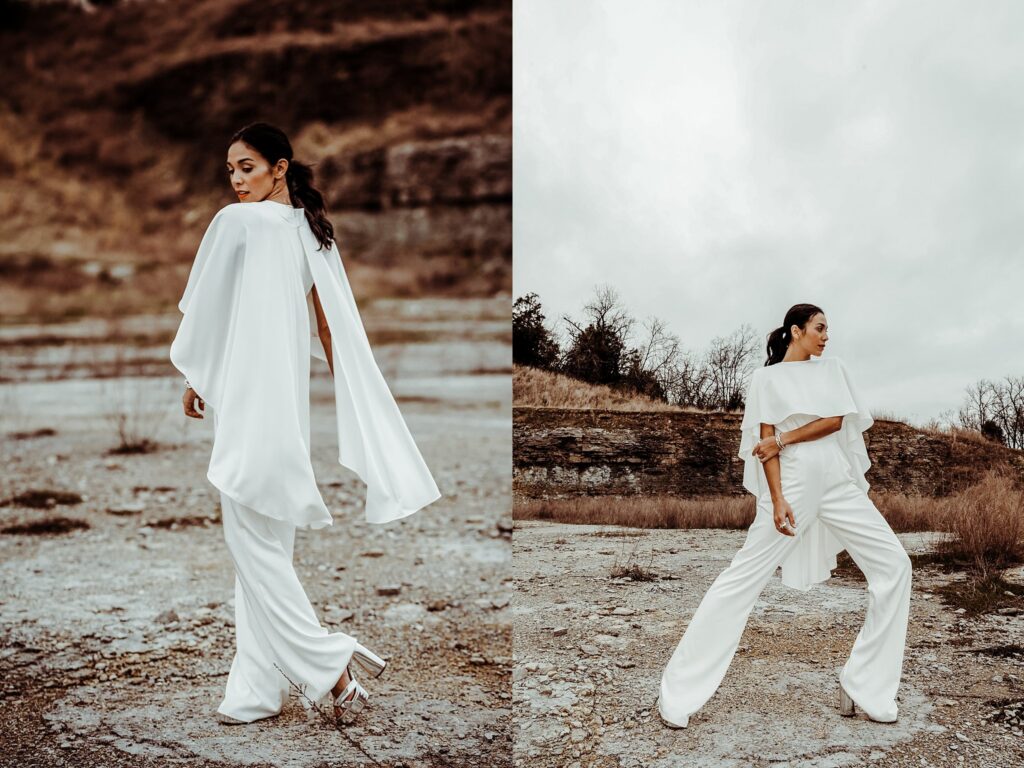 A woman in a flowing white outfit poses outdoors on rocky terrain, captured by a Nashville creative portrait photographer. She wears wide-leg pants and a dramatic cape-like top, set against earthy hills and cloudy skies.