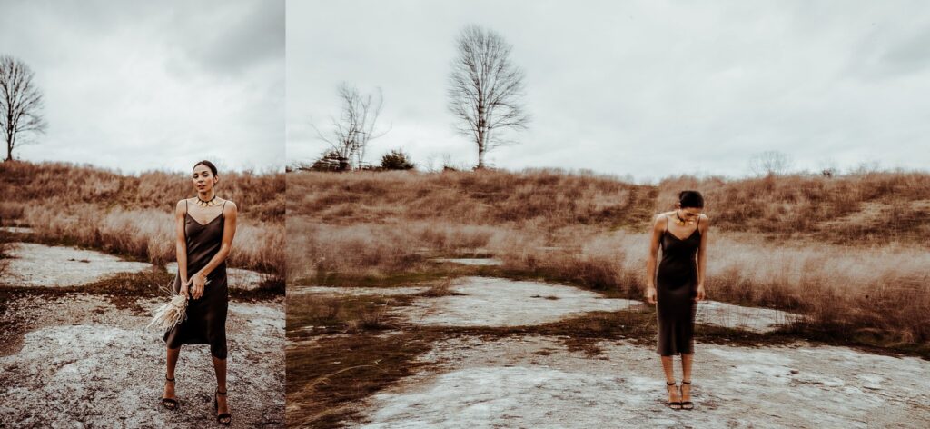 A woman in a dark dress stands outdoors on rocky ground, holding dried flowers. Captured by a Nashville creative portrait photographer, she appears twice: once upright and looking ahead, and once looking down in blurred motion among leafless trees and dry grass.