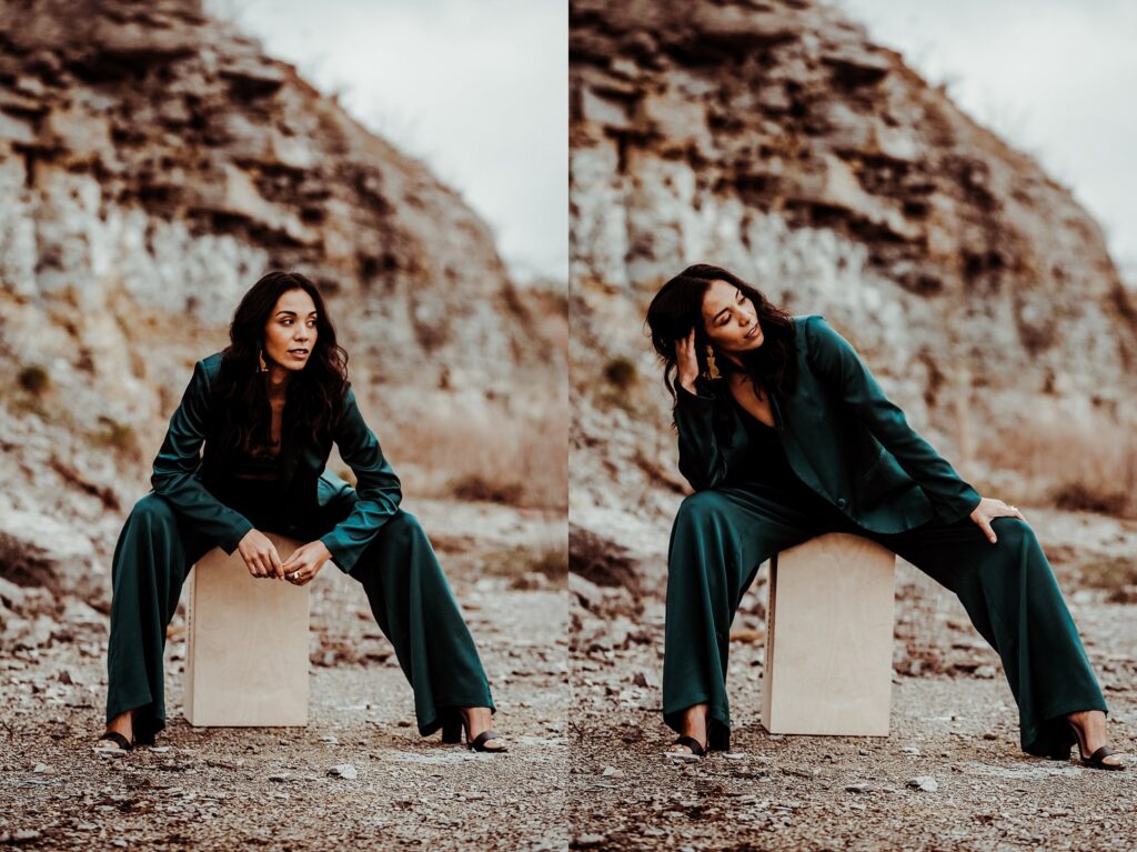 A woman in a dark green suit poses outdoors on a wooden box, sitting with legs apart on rocky ground—captured by a Nashville creative portrait photographer—against blurred cliffs and a cloudy sky. In one image, she gazes forward; in the other, she leans her head on her hand.