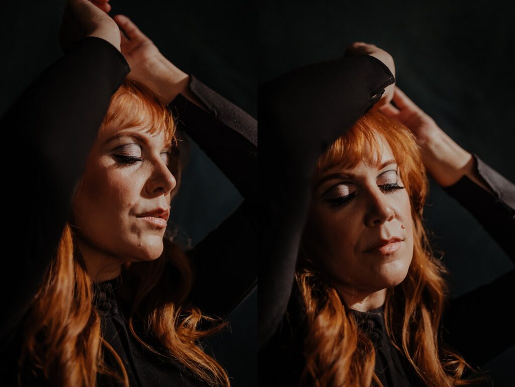 A woman with long red hair and closed eyes poses with arms raised above her head in two side-by-side portraits, wearing a black top against a dark background. Soft light highlights her face—a stunning work by a Nashville creative portrait photographer.