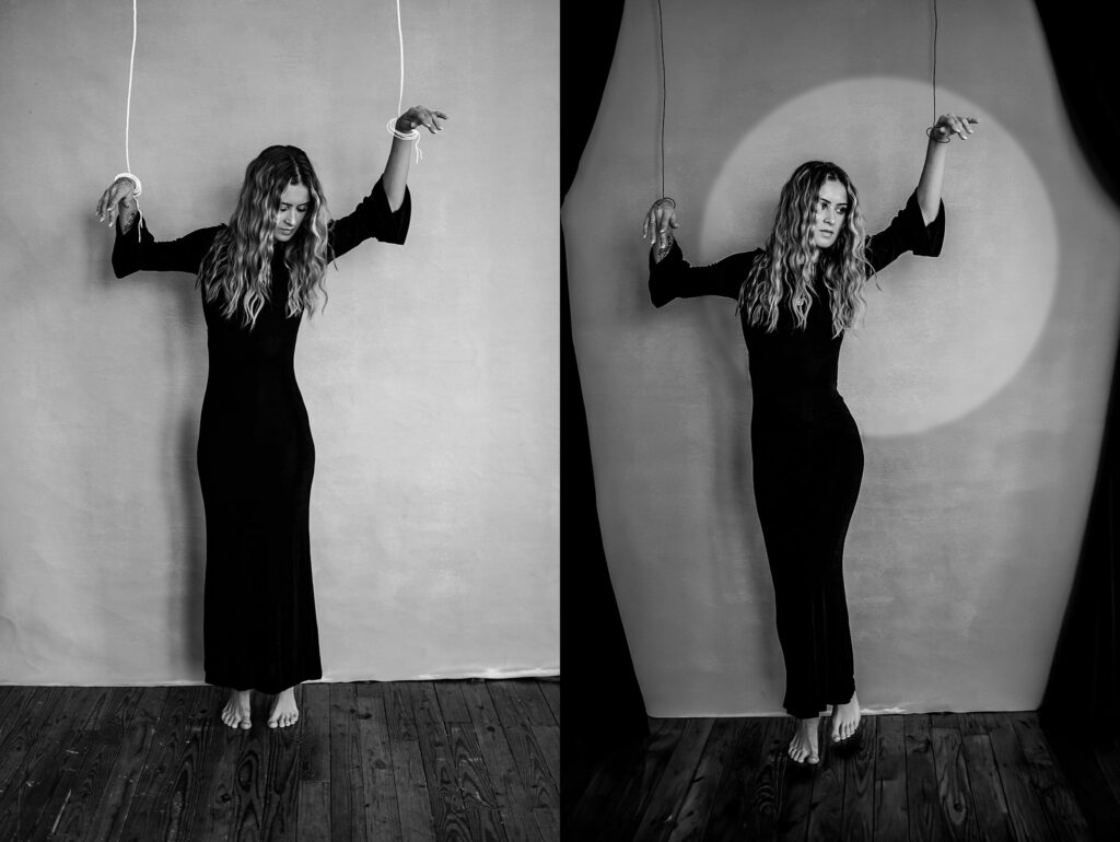 A woman in a long black dress stands barefoot against a wall, posed like a marionette with her wrists tied to strings—a striking black-and-white image by a Nashville creative portrait photographer. One side is evenly lit, the other features a spotlight effect.