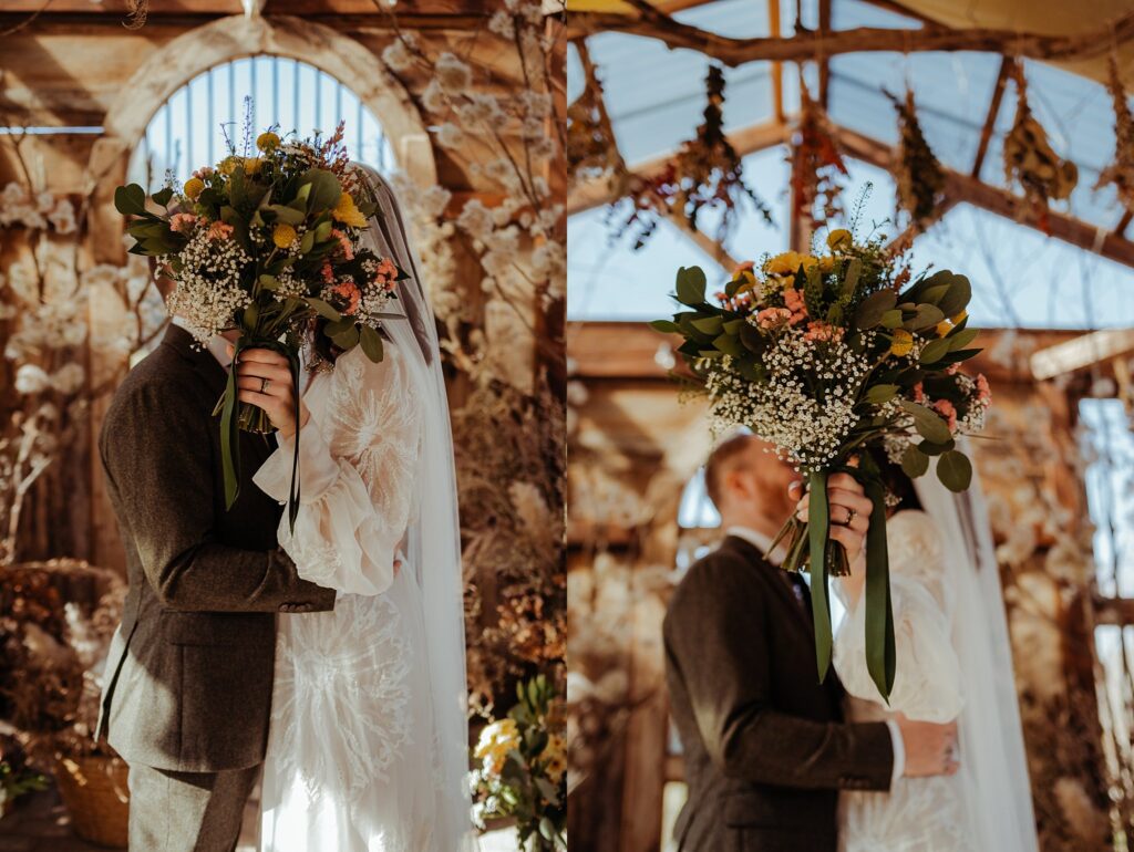 A bride and groom embrace indoors, their faces hidden behind a large bouquet of flowers. Captured by a Nashville wedding photographer, the scene features rustic wooden beams, dried florals, and natural light streaming through arched windows.