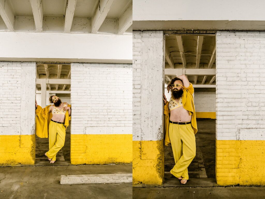 A person in yellow pants, a yellow jacket, and sunglasses poses confidently against a white and yellow brick wall in an industrial space—captured by a Nashville creative portrait photographer.