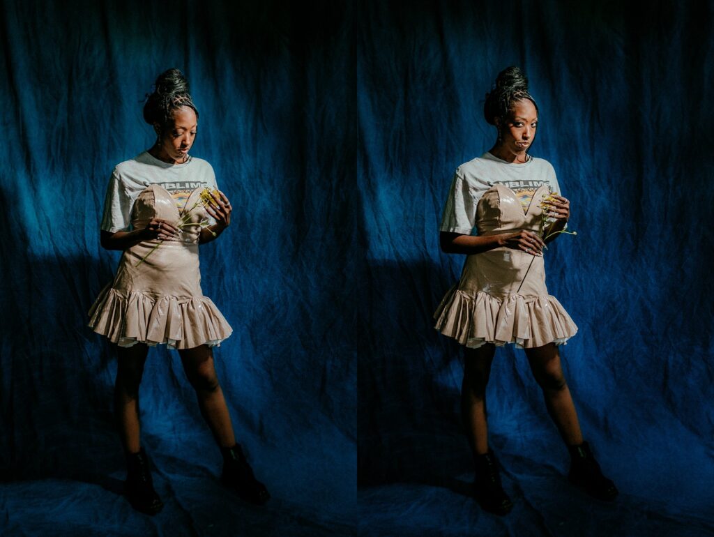 A woman stands against a dark blue backdrop, wearing a light ruffled skirt, graphic t-shirt, and black boots. Captured by a Nashville creative portrait photographer, she holds a flower—looking down in one image and facing forward in the other.